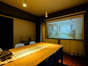 a large projection screen in a room with a wooden table at Home n Lounge in Tokyo