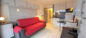 Una sala de estar con un sofá rojo y una cocina. en STUDIO PORT VAUBAN vue port excellente situation climatisé Fibre, en Antibes