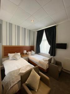 a hotel room with two beds and a chair and a window at The Strand Hotel in Blackpool