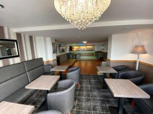 a restaurant with tables and chairs and a chandelier at The Strand Hotel in Blackpool +4 photos