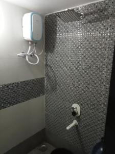 a bathroom with a shower with a toilet and a phone at Narmada Homestay in Garudeshwar