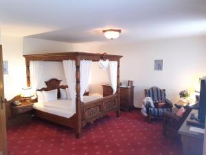 a bedroom with a canopy bed and a chair at Gasthaus Auerhahn in Baden-Baden