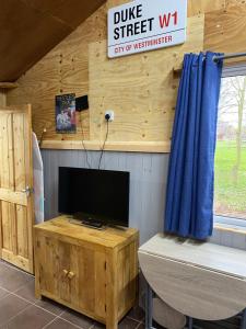 a living room with a tv on a wooden wall at The Woodland in Wyboston