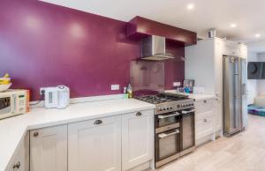 a kitchen with white cabinets and purple walls at Stylish Townhouse with views of Arundel Cathedral in Arundel