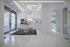 a white kitchen with a dining table and chairs at Diamond Luxury Villa Corfu 5 Bedroom Luxury Villa in Mesongi