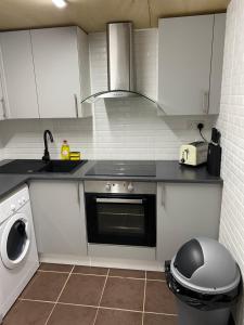 a kitchen with a stove and a sink and a washing machine at The Woodland in Wyboston