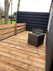 een houten terras met twee rieten stoelen erop bij The Woodland in Wyboston