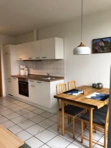 a kitchen with a wooden table and a kitchen with white cabinets at Apartments Schnepel in Sankt Michaelisdonn