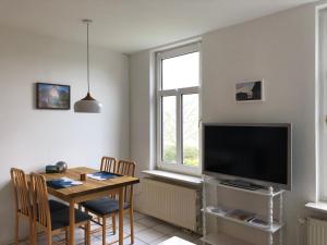Sala de estar con mesa de comedor y TV en Apartments Schnepel, en Sankt Michaelisdonn
