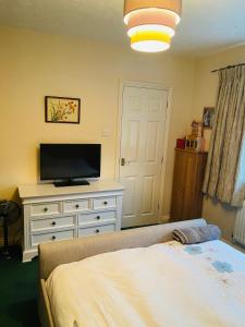 a bedroom with a bed and a dresser with a television at Beautiful double en-suite room in Oakham
