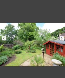 a person standing in a garden near a red building at Beautiful double en-suite room in Oakham