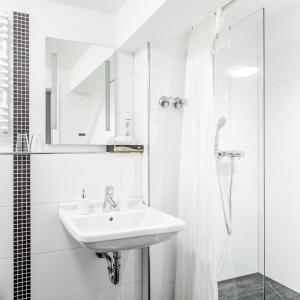 a white bathroom with a sink and a shower at Hotel am Museum Köln in Cologne
