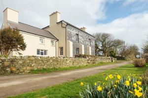 a stone house with a stone wall and flowers at Penrhiw Farm B & B in Goodwick