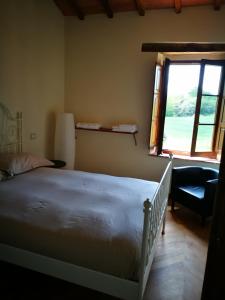 a bedroom with a bed and a window and a chair at Molino della Tuoma in San Quirico dʼOrcia