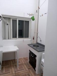 baño blanco con lavabo y ventana en Apartamento 6 pessoas AP 01, en Torres