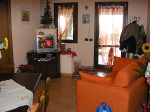 a living room with an orange couch and a tv at Baglio Makari in San Vito lo Capo