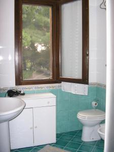 a bathroom with a sink and a toilet and a window at Baglio Makari in San Vito lo Capo