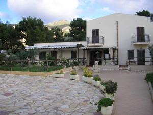 a white building with potted plants in front of it at Baglio Makari in San Vito lo Capo