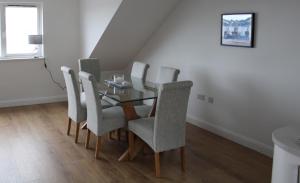 una sala da pranzo con tavolo in vetro e sedie di SEACLIFF ROAD APARTMENT a Bangor