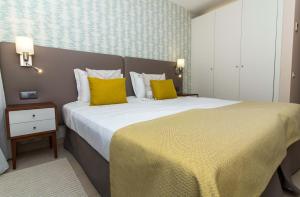 een slaapkamer met een groot bed met gele kussens bij Coco Design Apartment Salgados Beach - By Dalma Portuguesa in Galé +29 foto's