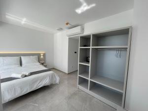 a white bedroom with a bed and a tv at La Veranda Hotel in Larnaca