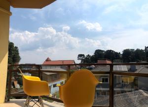 2 sillas amarillas sentadas en un balcón con vistas en Apartamento completo no centro de Gramado en Gramado