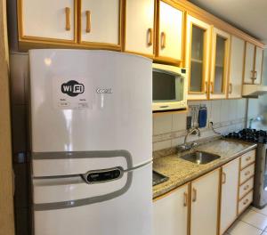 La cocina está equipada con nevera blanca y armarios de madera. en Apartamento completo no centro de Gramado en Gramado