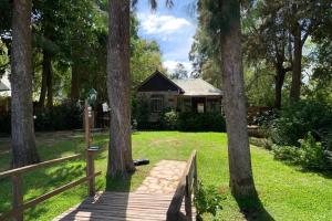 un puente de madera frente a una casa con árboles en La Escondida, alquiler casa en el delta, en Tigre