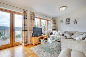 ein Wohnzimmer mit einem weißen Sofa und einem TV in der Unterkunft The Old Stables Aberdyfi apartment 6 in Aberdyfi