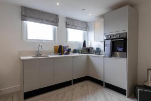 a kitchen with white cabinets and a sink and a microwave at Victoria House by Tŷ SA in Cardiff