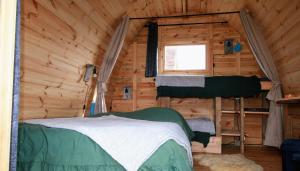 a bedroom in a log cabin with a bed and a window at Cabane Les Pourettes in Feusines