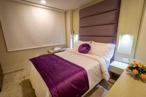 a bedroom with a large bed with a purple blanket at Hotel Trugo Boutique Armenia in Armenia