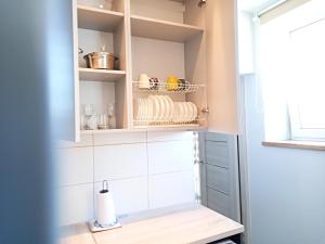 a kitchen with white tiled walls and white cabinets at Klaipeda city center apartment in Klaipėda