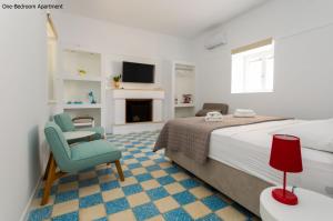 a bedroom with a bed and a chair and a tv at Aria Apartments in Spetses