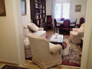sala de estar con sillas blancas y mesa en George appartment, en Atenas