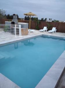 una piscina azul con 2 sillas y una sombrilla en Conil de la Frontera - Casa La Ilusión, en Conil de la Frontera