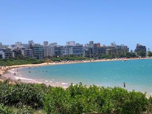 a beach with people in the water and buildings at Apartamento Peracanga com Wi-Fi in Guarapari