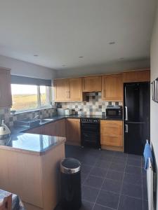 a kitchen with wooden cabinets and a black refrigerator at Loughinvar, Newtownards in Newtownards