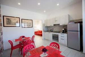 a kitchen with red chairs and a table and a kitchen with a refrigerator at Gemelli Sweet Holiday in Rome