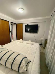 1 dormitorio con 1 cama blanca grande y TV de pantalla plana en Departamento 1A Santiago del Estero 80 en Salta