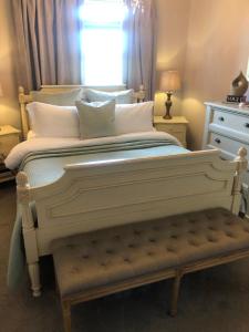 a large white bed with a bench in a bedroom at Woodend Cottage in Dumfries