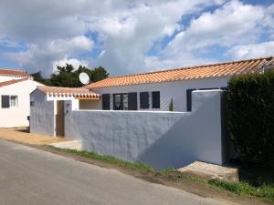 ein weißes Haus mit einem Zaun neben einer Straße in der Unterkunft Maison Bord de Mer au Vieil 3 étoiles in Noirmoutier-en-l'lle