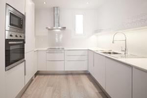 バルセロナにあるカサノバ　チャーム　4BDR　アパートメントの白いキッチン(白いキャビネット、シンク付)