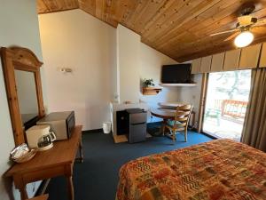 ein Hotelzimmer mit einem Bett, einem Schreibtisch und einem Tisch in der Unterkunft Whispering Pines Lodge in Kernville