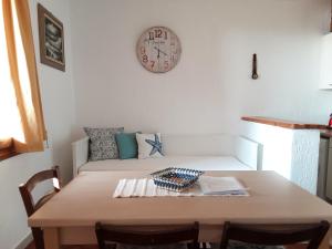 una stanza con tavolo e orologio sul muro di Baia Santa Reparata, grazioso bilocale con vista mare - IUN Q2157 a Santa Teresa di Gallura