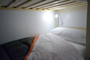Łóżko w małym pokoju z białą ścianą w obiekcie Santander Central Hostel w mieście Santander