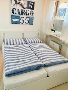a bed with blue and white striped sheets in a room at Ferienwohnung "Dahme & Strandkorb" in Dahme