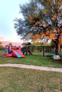 un parque infantil con un tobogán y un árbol en La Maína Cabañas en San Javier