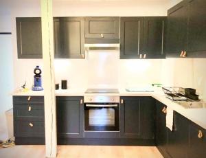 a kitchen with black cabinets and an oven at Une maison design dans le centre ville in Foix