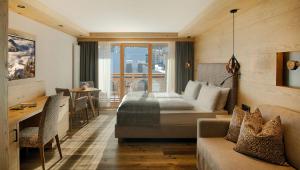 a bedroom with a bed and a table and a couch at Hotel Villa Eden in Corvara in Badia